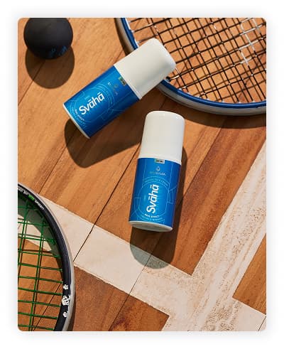 A bottle of Svaha Topical Pain Cream displaying with the backdrop of tennis racquets