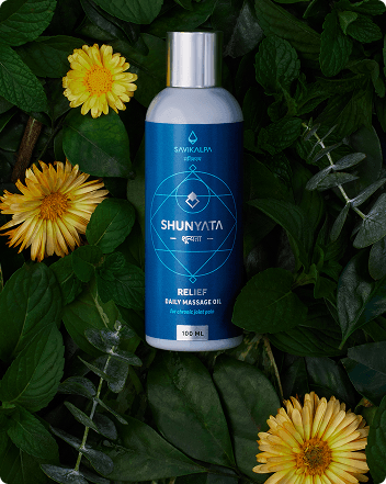 A bottle of Shunyata Relief Oil displaying over a bed of leaves and few flowers as the backdrop